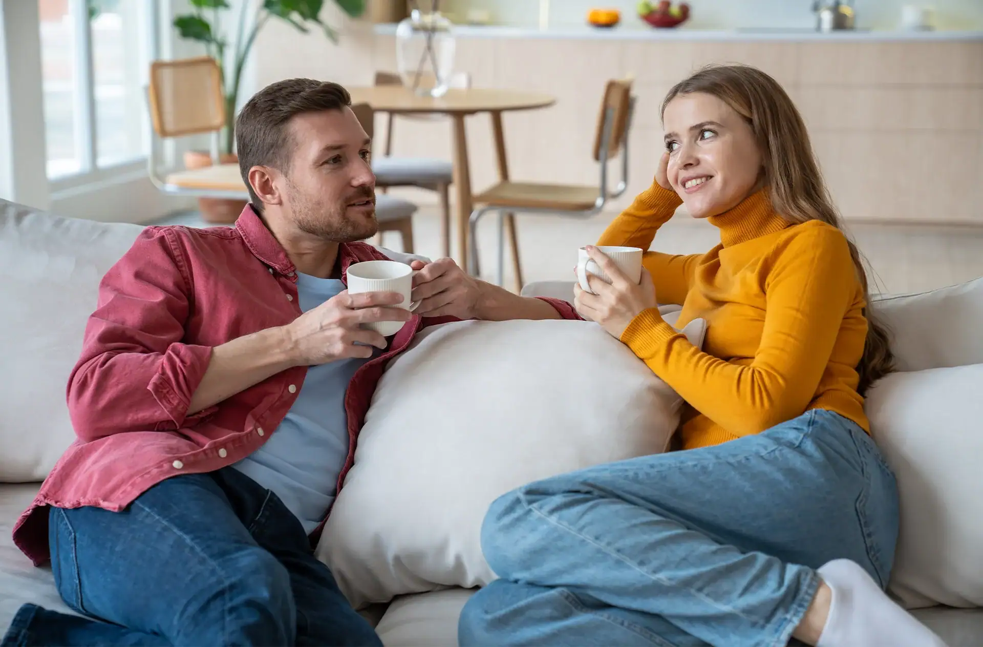 Two coffee mugs on a table connected by a bridge of light, representing the connection achieved through improved communication in marriage.