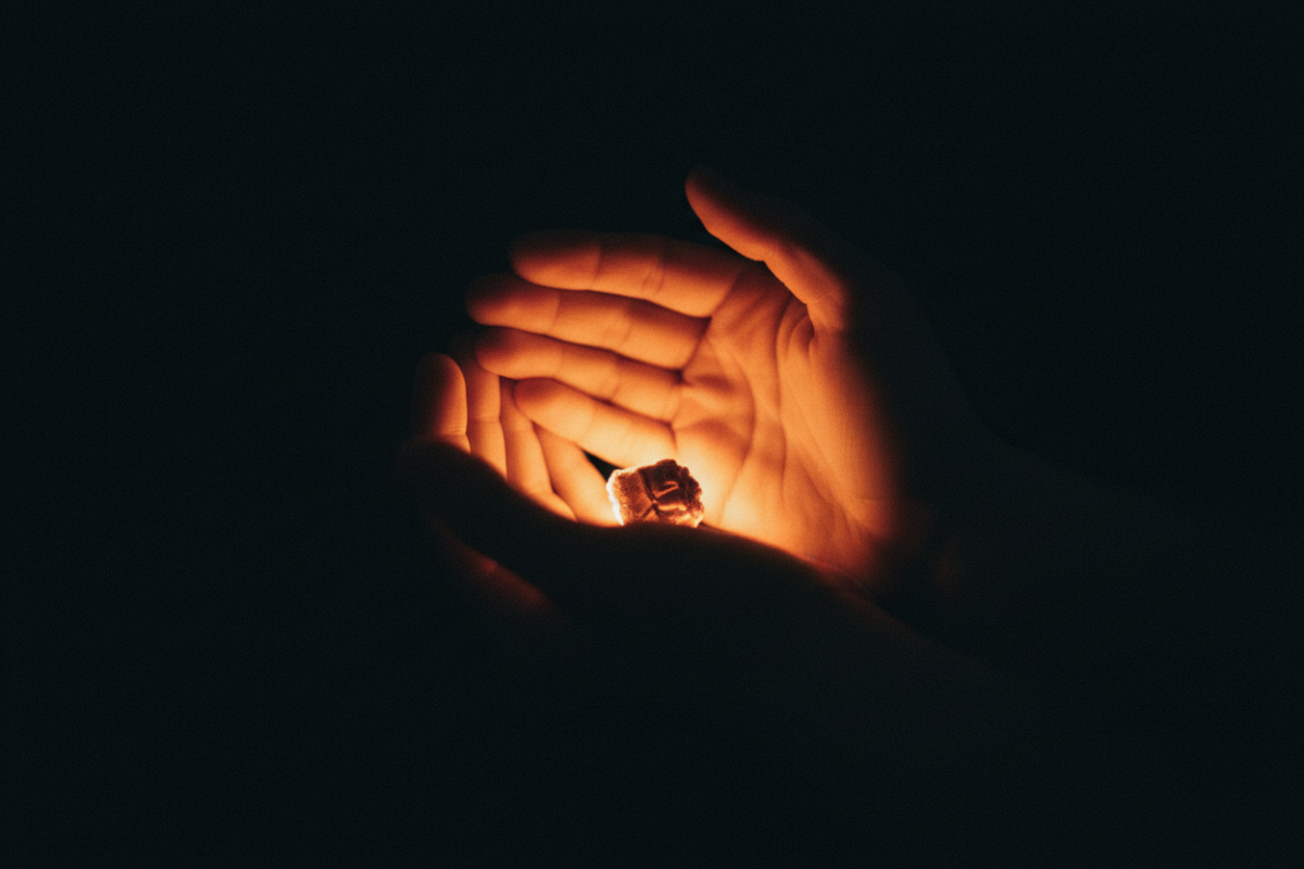 Two hands carefully holding a glowing ember, symbolizing the process of rekindling intimacy and passion through couples therapy.