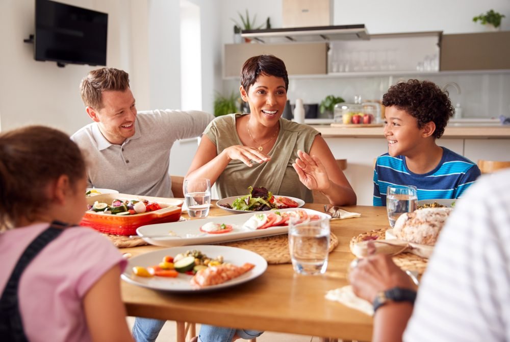 A happy blended family eating dinner together, representing the unity and new traditions built through family counseling.