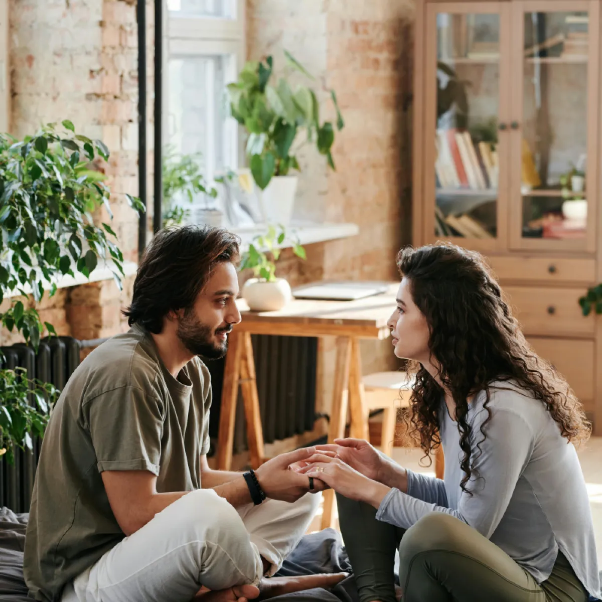 A couple holding hands and talking vulnerably, representing the successful management of jealousy through open communication.