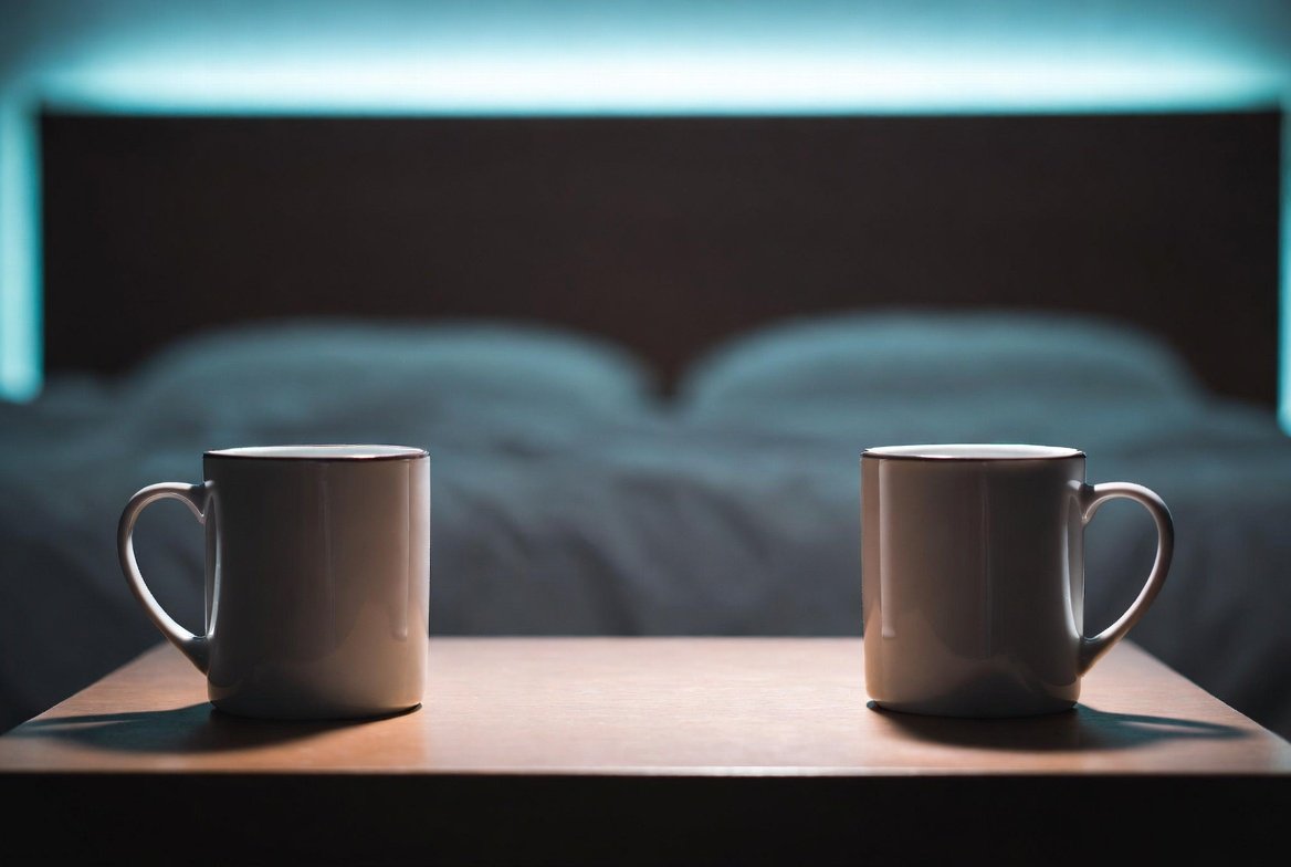 Two coffee mugs on opposite sides of a nightstand, representing the emotional distance and loss of intimacy in a sexless marriage.