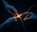 Two hands reaching for each other with glowing golden light between them, symbolizing the emotional bond repair in emotionally focused therapy.